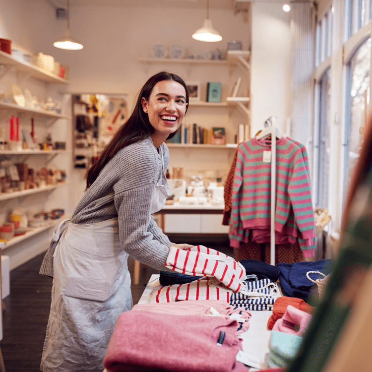 A woman folding some clothes in a shop